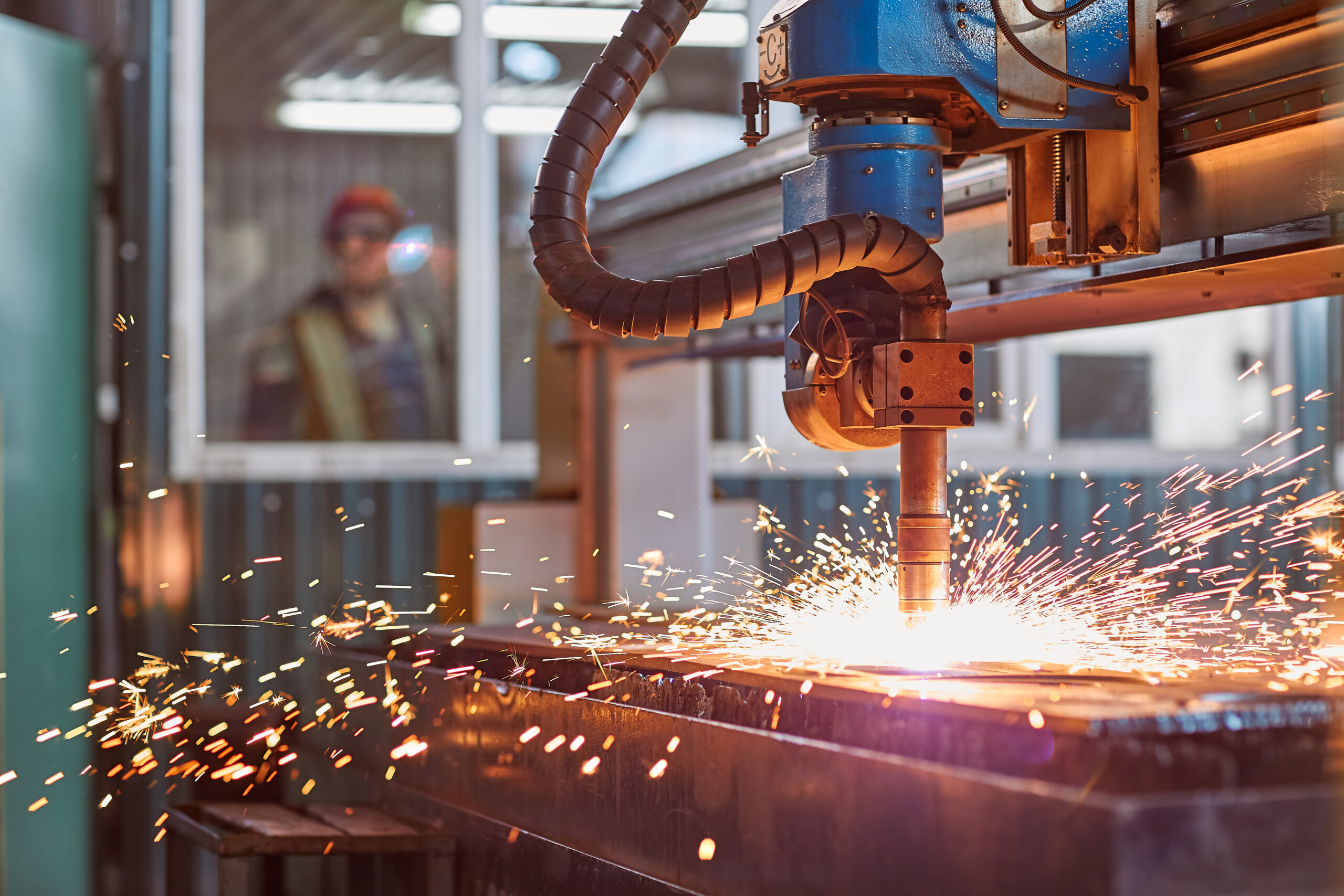CNC laser plasma. Selective focus on modern technology laser plasma cutting of metal in process at metalworking factory male worker on background copyspace